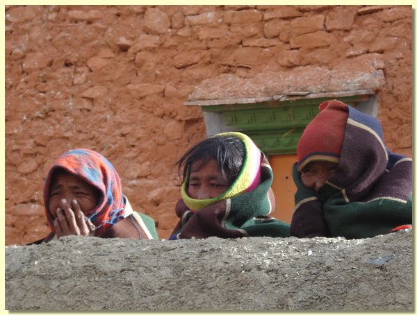 Drei Gesichter ueber der Mauer vor der Gompa.JPG