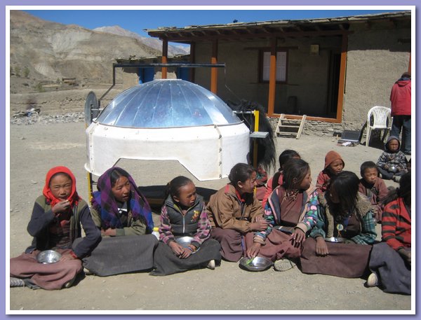 Die Kinder warten vor dem umgestuelpten Solarkocher auf das Mittagessen.JPG