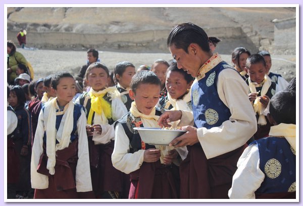 Der Lehrer Tenzin Namdrol verteilt Sssigkeiten.JPG