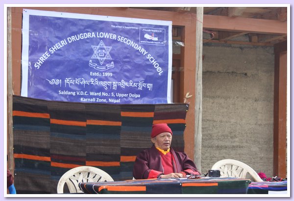 Schirmherr der Schule, Nyima Lama, unter dem Schulschild sitzend.JPG