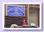 Schirmherr der Schule, Nyima Lama, unter dem Schulschild sitzend.JPG